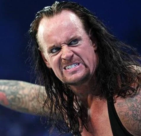 Close-up of The Undertaker snarling in the wrestling ring with long hair and intense eyes