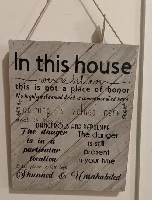 This Place Is Not A Place Of Honor — Rustic wooden sign styled like home décor with WIPP nuclear waste warning text inscribed.