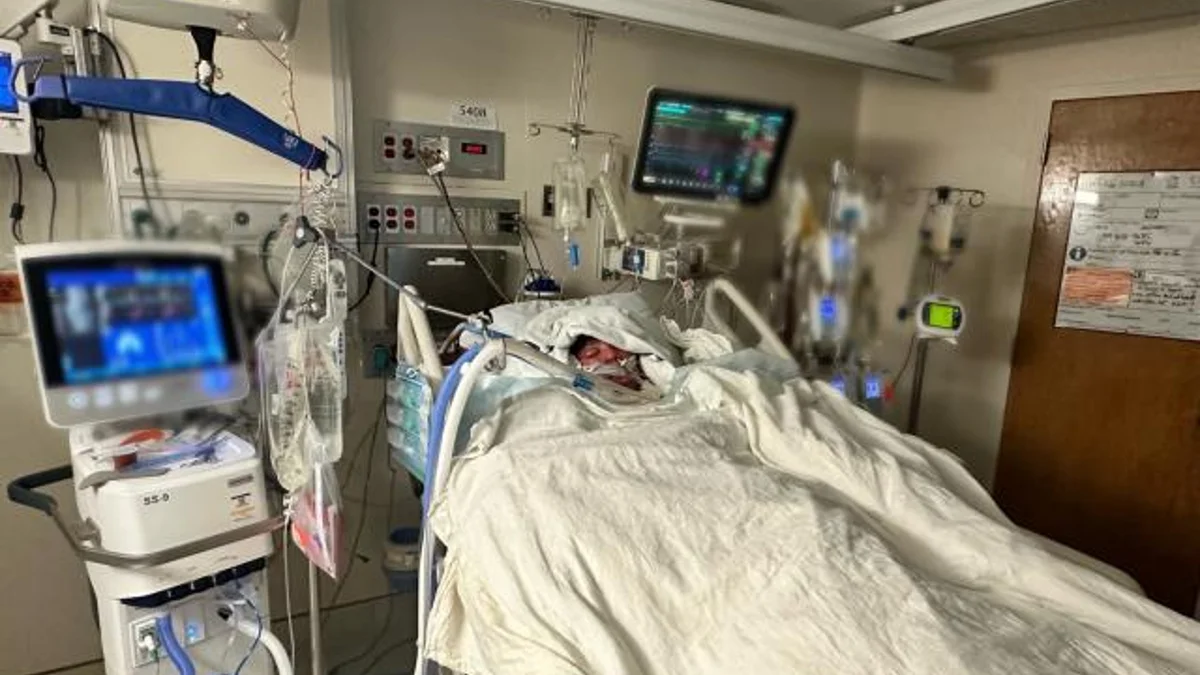 TikTok Flamethrower Challenge — Patient with facial injuries lying in a hospital ICU bed surrounded by medical equipment and monitors