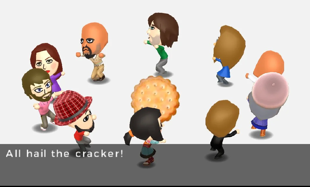 Tomodachi Life — Mii characters worshipping a giant cracker with caption 'All hail the cracker!'