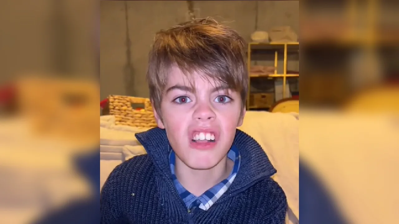 Topher TikTok (TopherTok) — Young boy with brown hair snarling at the camera, wearing a navy sweater over a blue plaid shirt