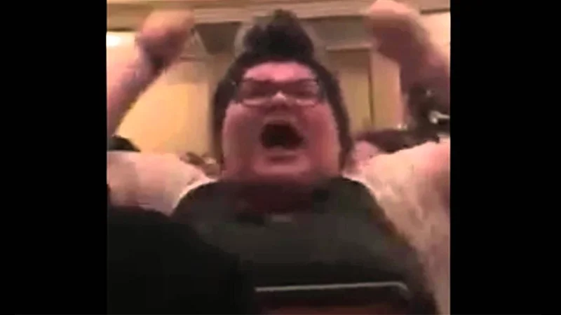 Trigglypuff — Woman with glasses screaming with raised fists at a panel event