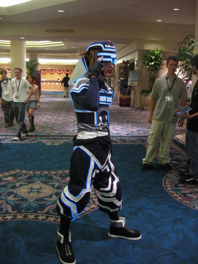 Cosplayer in a Tron-style costume with glowing blue lines at a convention