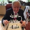 Trump Is Playing 4D Chess — Photograph of Donald Trump seated at table with standard chess set.
