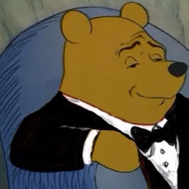 Tuxedo Winnie Pooh — Winnie the Pooh sits in blue armchair wearing black tuxedo and bow tie.