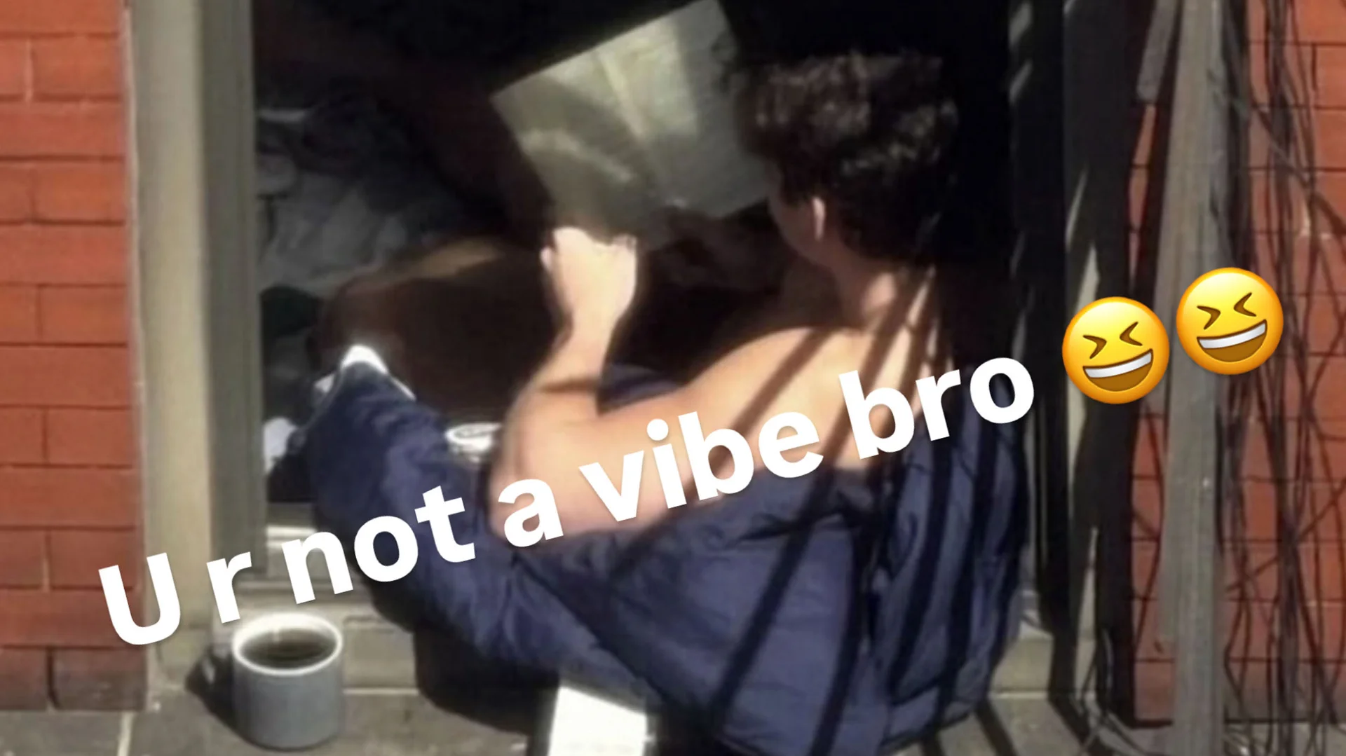 Man reading a book while sitting on a brick building windowsill with 'U r not a vibe bro' caption and laughing emojis.