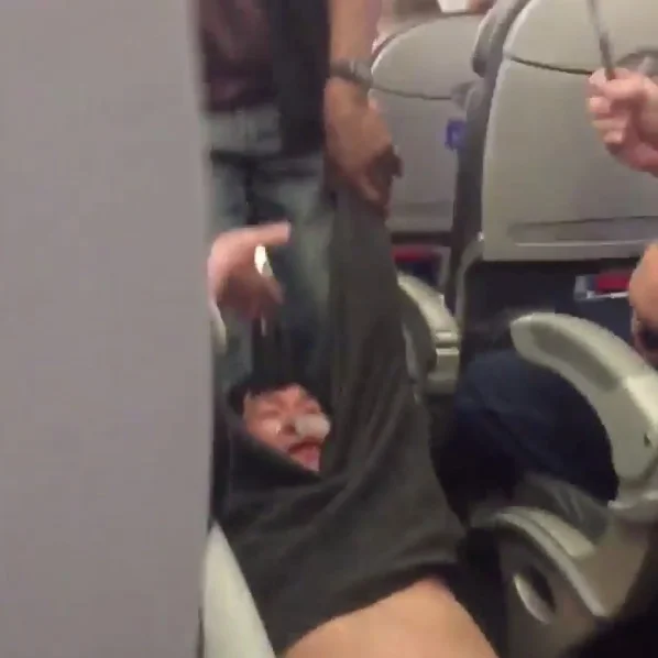 United Airlines Passenger Removal — Bloodied passenger being dragged down airplane aisle by security