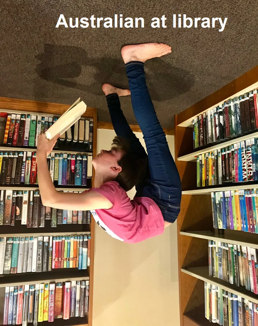 Upside-Down Australia — Person doing a handstand reading a book in library stacks, captioned 'Australian at library'