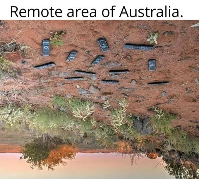 Upside-Down Australia — Flipped photo of remotes lying on red outback dirt with caption 'Remote area of Australia.'