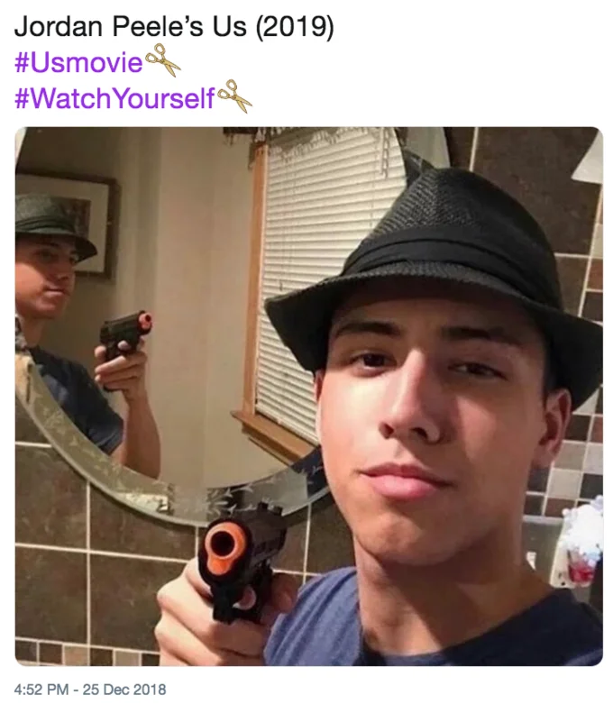 Us (2019 Film) — Young man in a fedora pointing a toy gun at his reflection in a mirror, captioned as Jordan Peele's Us (2019).