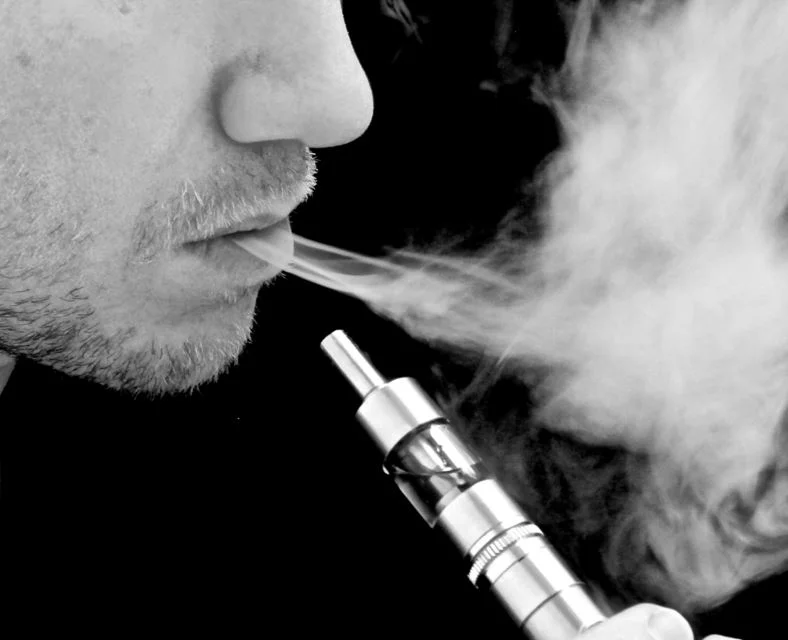 Vaping — Black and white close-up of a man exhaling vapor from a metal vape mod