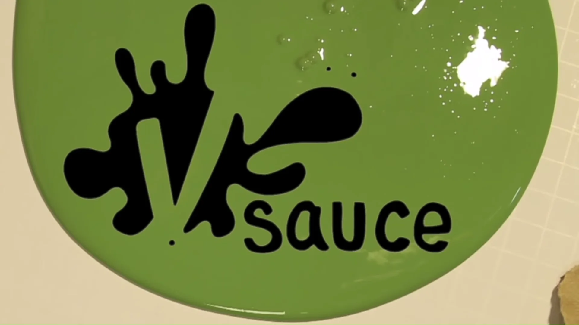 Vsauce logo in black splatter font on a green painted surface