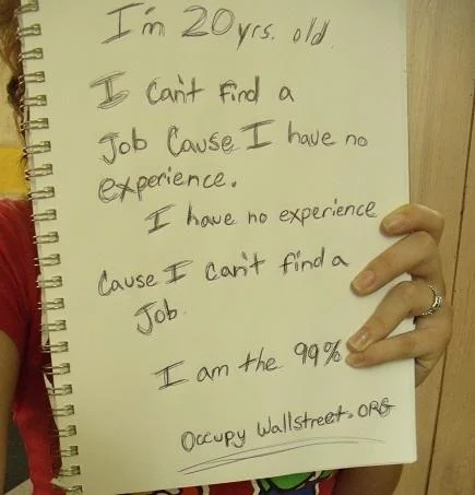 We Are The 99 Percent — Spiral notebook sign about unemployment catch-22, ending 'I am the 99%'.
