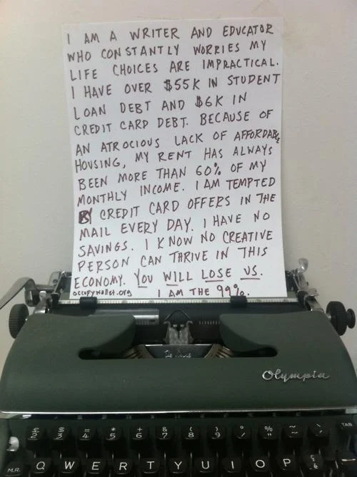 We Are The 99 Percent — Handwritten statement in an Olympia typewriter describing writer's debt and ending 'I am the 99%'.