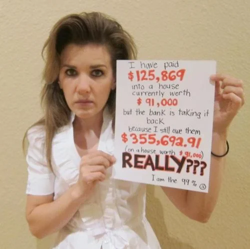 We Are The 99 Percent — Young woman holds a sign about an underwater mortgage, saying she is the 99 percent.