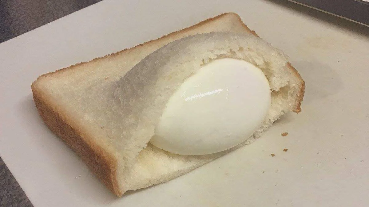 We Have Food at Home — Slice of white bread with a whole peeled hard-boiled egg sitting in a scooped-out hollow