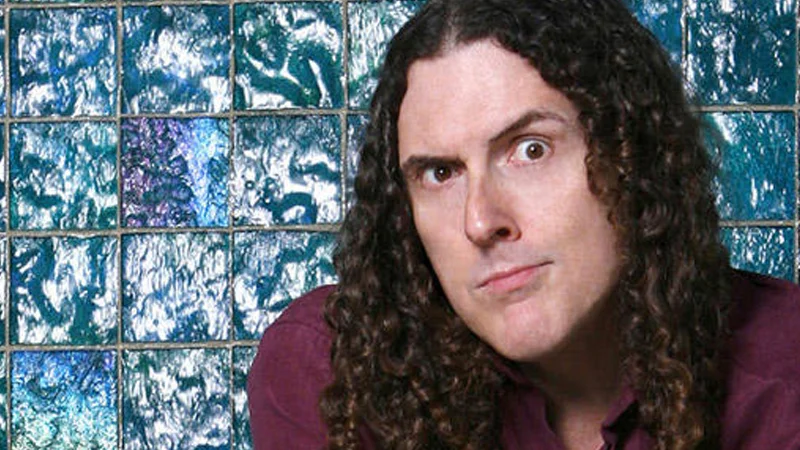 "Weird Al" Yankovic — Weird Al Yankovic portrait with long curly hair against a blue tiled background