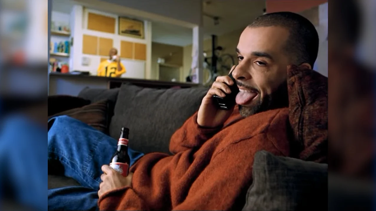 Whassup? — Man on couch holding Budweiser bottle and phone, tongue out, from 1999 Whassup commercial