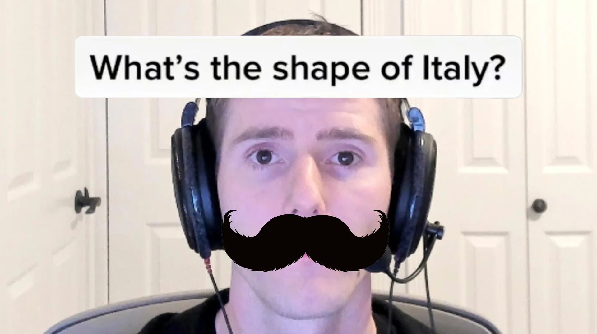 Man in headphones with a drawn-on handlebar mustache under the caption 'What's the shape of Italy?'