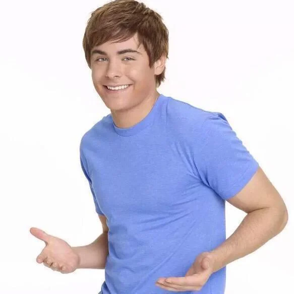 When Your Parents Ask Where All Your Money Went — Zac Efron in blue t-shirt gesturing with both hands as if presenting something
