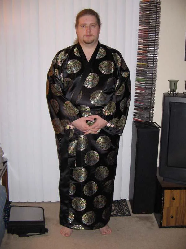Ken-Sama — Full-body photo of a man wearing a long black kimono standing in a 2000s-era living room.