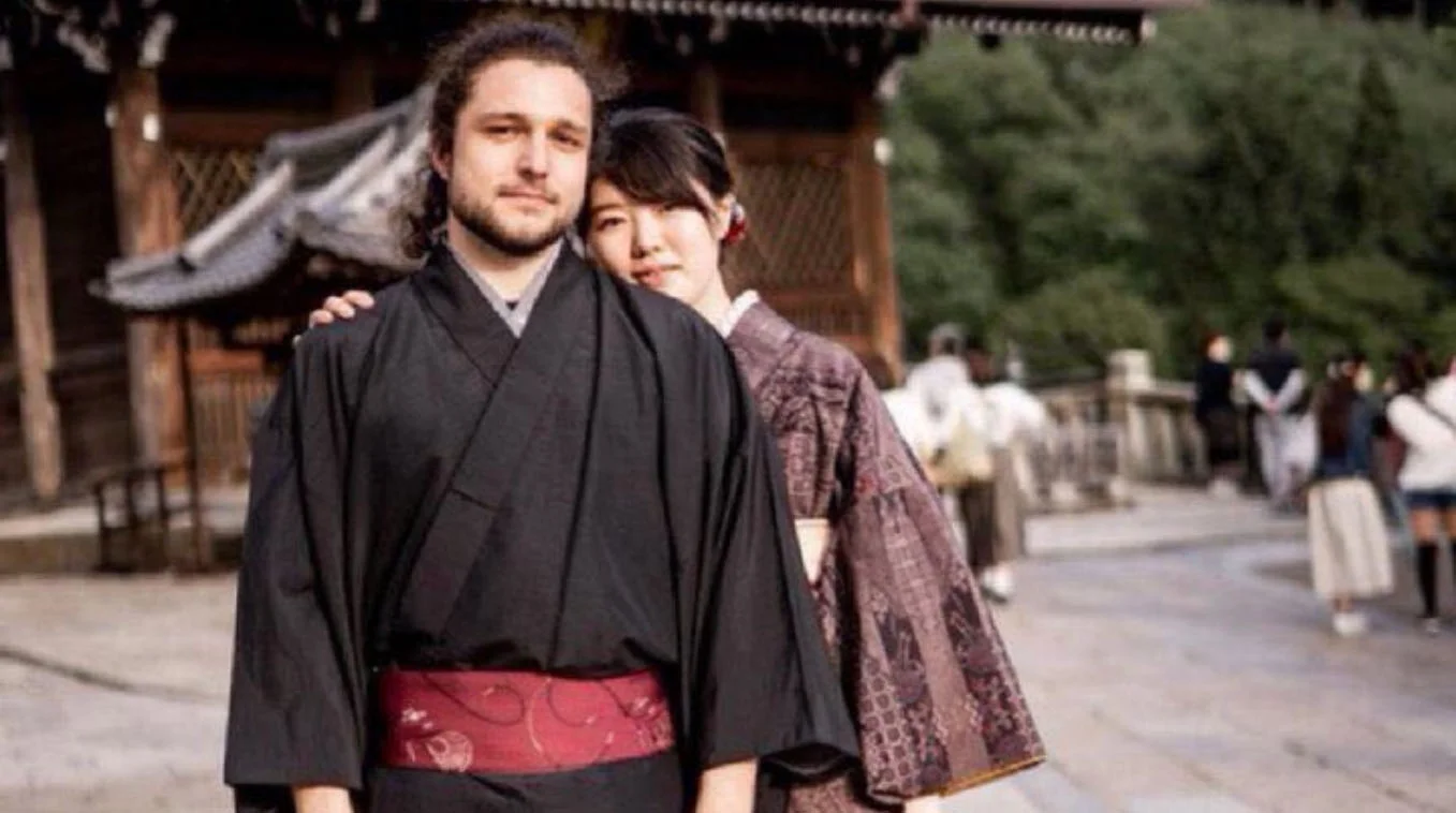 White Man In A Kimono — White man in a black kimono with a Japanese woman leaning on his shoulder outside a Japanese temple