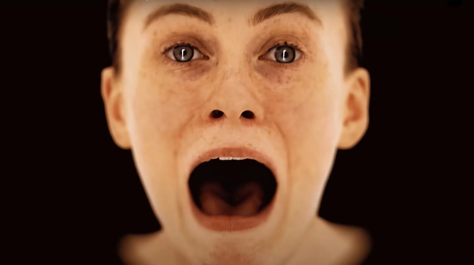 White Woman Scream GIF — Close-up of a white woman screaming with mouth wide open against a black background.