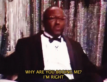 Why Are You Booing Me I'm Right — Animated GIF version of the meme featuring formally-dressed man with yellow text caption 'WHY ARE YOU BOOING ME? I'M RIGHT'.