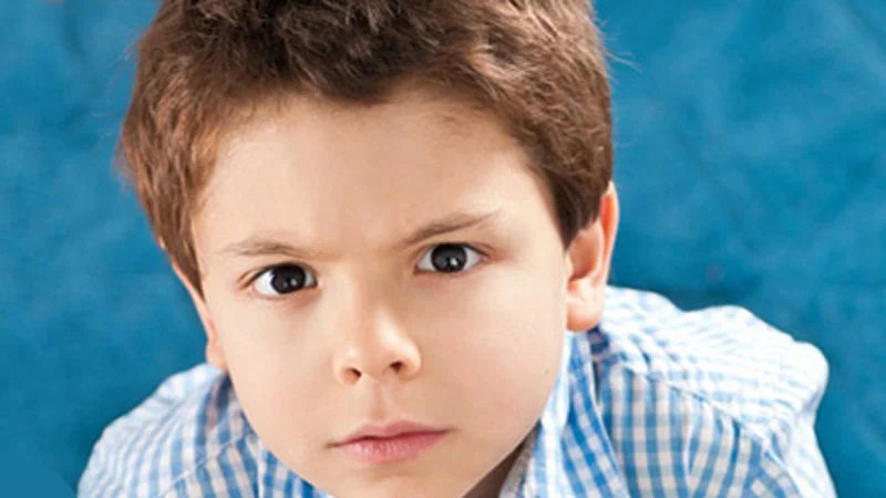 Why Didnt You Invest In Eastern Poland — Professional portrait of stern-faced child on textured blue background without text overlay.