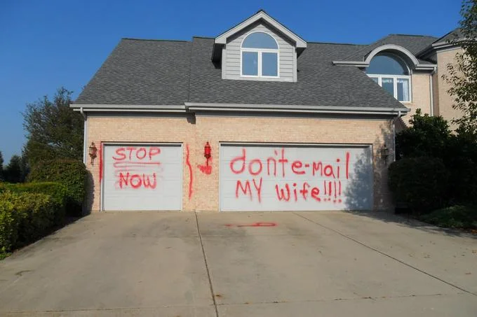 Wife Guys — House garage door spray-painted in red with the words 'don't e-mail my wife'