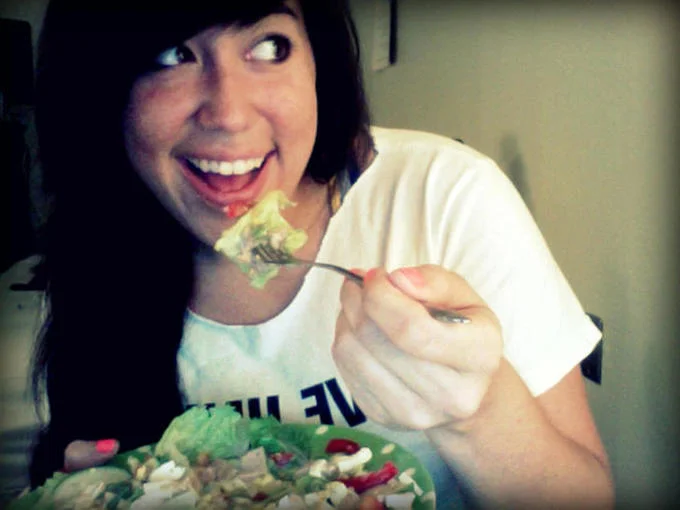 Women Laughing Alone With Salad — Instagram-filtered photograph of woman laughing while holding fork over large bowl of salad.