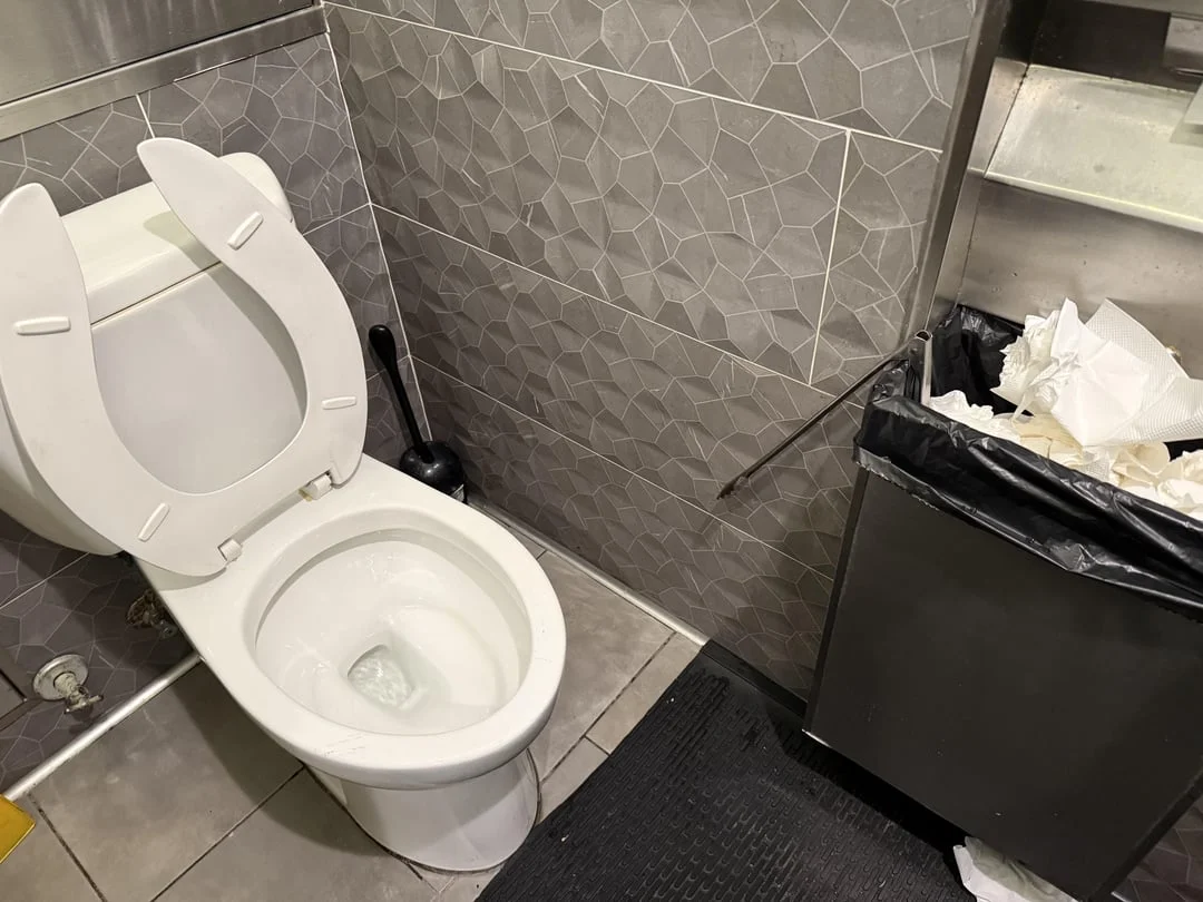 WTF — Public restroom toilet with a plunger stuck inside the bowl