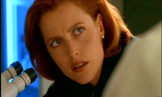 X-Files — Dana Scully looking up from a microscope with a puzzled expression