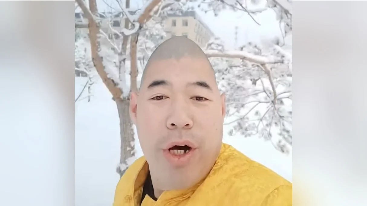 Xue Hua Piao Piao — Bald man in yellow robe singing outdoors in front of a snowy tree