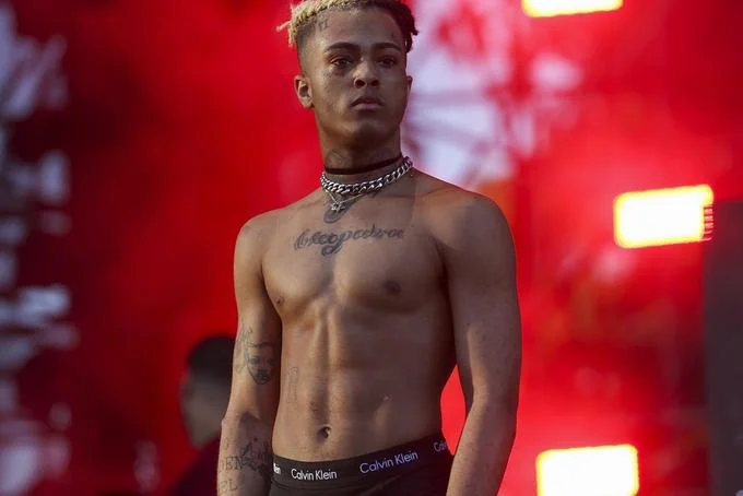 XXXTentacion performing shirtless on stage with red background