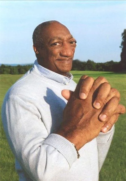 Yaoi Hands — Outdoor photo of person in white sweater with large clasped hands in foreground.