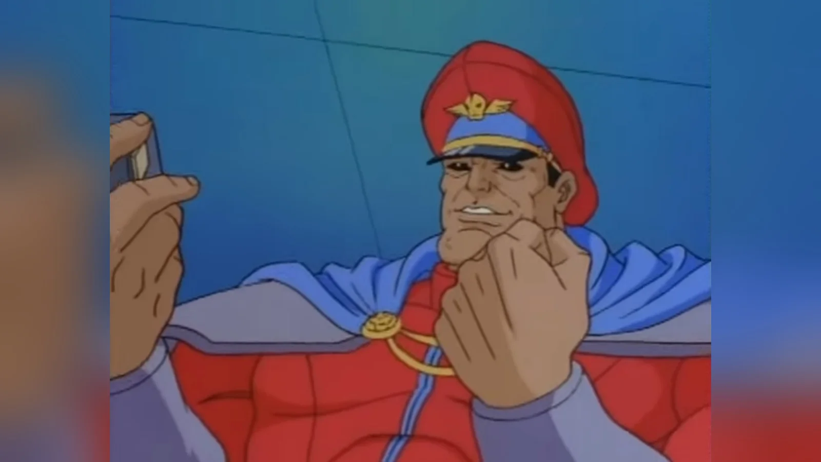 Yes! Yes! — M. Bison from Street Fighter cartoon grinning while holding a small device