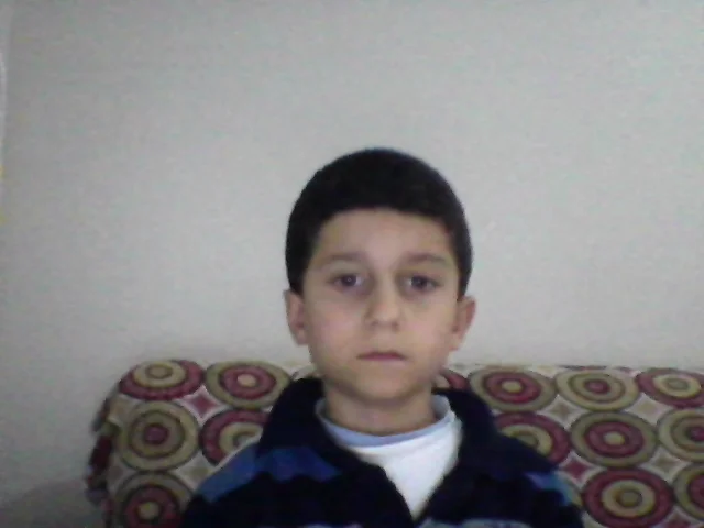 Yotube — Full webcam photo of young boy sitting on patterned couch with blank expression