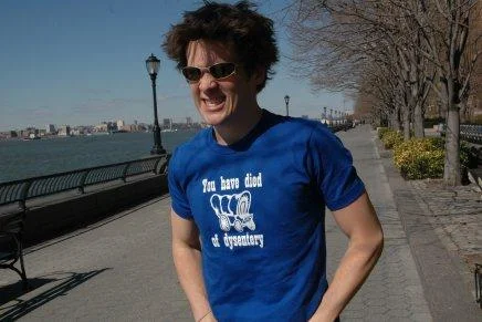 Person wearing blue t-shirt with 'You have died of dysentery' text and covered wagon illustration.