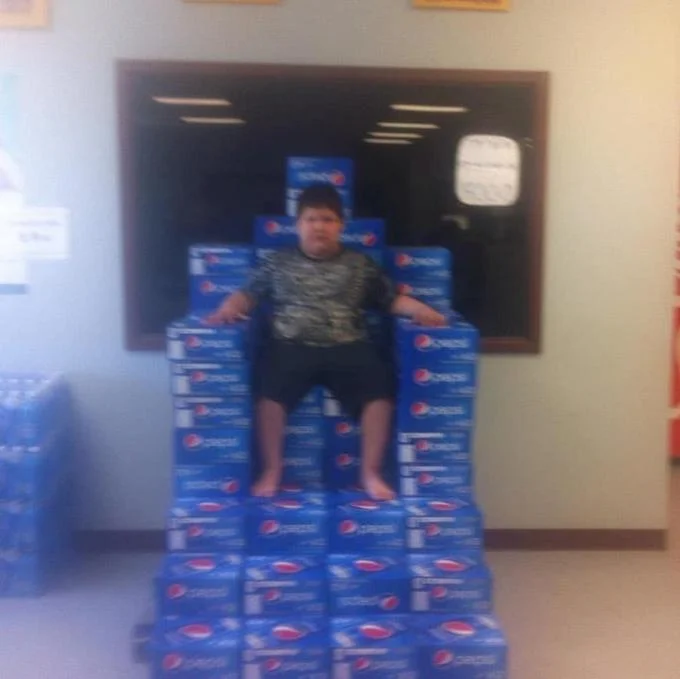 Your Politics Bore Me — Boy in camouflage shirt seated on a staircase throne made of stacked Pepsi cases