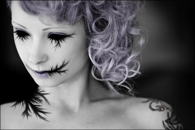 Woman with purple hair wearing Zalgo-themed makeup with spiky dark lines on face