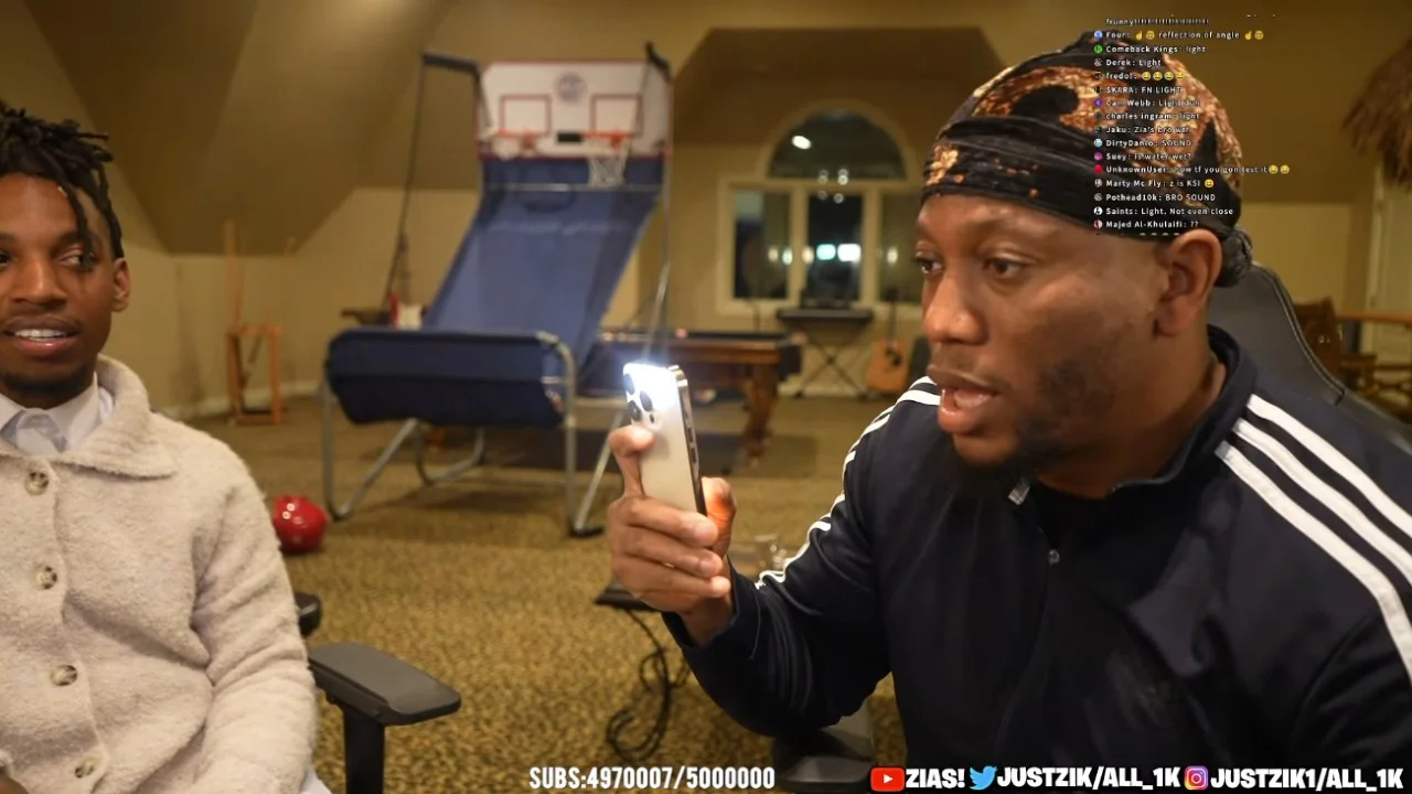 Zias and B.Lou's Sound Faster Than Light Test — Zias and Blou during a livestream, with Blou pointing an iPhone flashlight at the camera while chat debates